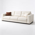 Cream leather sofa with boxy arms, a segmented backrest and brown and cream throw pillows on a white studio backdrop