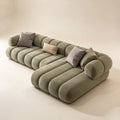 Sage-grey cloud sofa with segmented rounded cushions and loose throw pillows on a beige floor