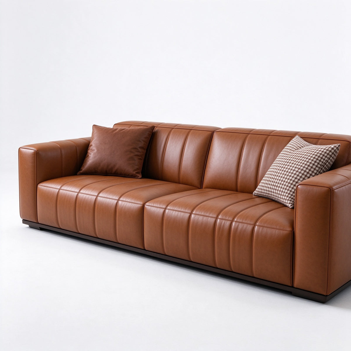 Three-seat view of the cognac leather sofa with a houndstooth cushion on a white studio floor