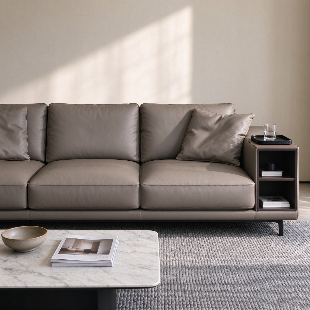 Three-seat view of the taupe leather sofa with a marble coffee table and the side table shelf detail